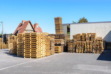 New And Used Wooden Pallets Stacked Outdoors In The Courtyard Of A Warehouse On A Sunny Day.