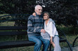 © Annatamila - Elderly man and woman couple, sitting on park bench hugging and enjoying summer outdoor