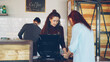 © silverkblack - Attractive woman talkative cashier is accepting contactless payments with mobile phone and talking to customers