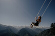 Dream and travel concept, Young beautiful woman enjoying  on swing flying in the sky over stunning mountain gorge