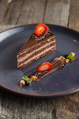 Wall Mural - slice of chocolate cake with fresh strawberry on a plate and cup of tea on the table