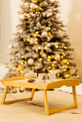 Wall Mural - A wooden tray stands on the bed against the backdrop of Christmas lights. On the tray is a jar of cookies and two cups.