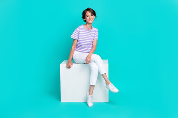 Sticker - Full length photo of sweet cute girl dressed purple t-shirt sitting cube chair smiling isolated teal color background