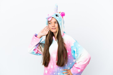 Wall Mural - Little caucasian girl wearing unicorn pajama isolated on white background listening to something by putting hand on the ear