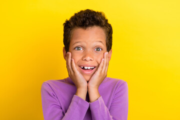 Canvas Print - Photo of astonished schoolkid beaming smile arms touch cheekbones isolated on yellow color background