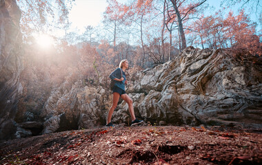 Wall Mural - Active lifestyle. Trekking and hiking. Young woman with rucksack in the rocks forest.