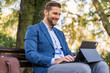 © DusanJelicic - Portrait of happy entrepreneur working on laptop\tablet while sitting on park bench.