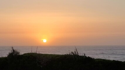 Wall Mural - Minimalistic soft sunset over the flowing sea water in Nazare