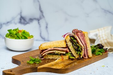 Wall Mural - Tasty fresh ham sandwich served on the wooden board with a bowl of salad