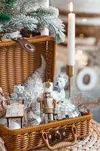Cozy Winter Concept. Home Warmth In Cold, Frosty Weather. Still-life. Christmas Toys, Wicker Basket, Candles And Fir Branches On The Coffee Table In The Living Room Home Interior.