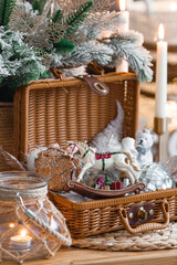 Wall Mural - Cozy winter concept. Home warmth in cold, frosty weather. Still-life. Christmas toys, wicker basket, candles and fir branches on the coffee table in the living room home interior.