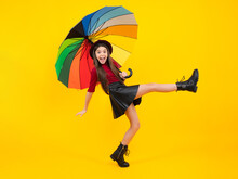 Child Teenager Girl With Umbrella In Autumn Black Leather Skirt Boots And Hat Isolated On Yellow Studio Background. Excited Teenager, Glad Amazed And Overjoyed Emotions.