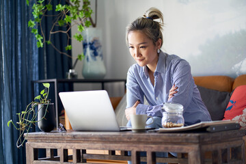 Wall Mural - mature asian woman working from home using notebook computer