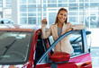 Photo of happy young woman showing key to her new car. Concept for car rental