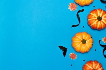 Wall Mural - Halloween concept, Scary smile pumpkin and black bat with maple leaves on light blue background