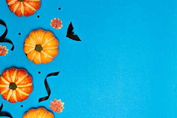 Wall Mural - Halloween concept, Scary smile pumpkin and black bat with maple leaves on light blue background