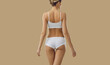 Rear view of toned slim woman in underwear isolated on yellow studio background show good body shape. Thin girl in underclothing garment advertise fashion intimate wear. Diet and wellness concept.