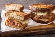 classic beef patty melt sandwich using crispy rye bread, cheese, and tender onions closeup on the wooden board on the table. Horizontal