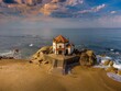 © Martinho Carvalho/Wirestock Creators - Catholic church Capela do Senhor da Pedra on the beach at sunset