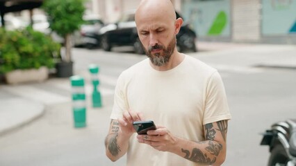 Sticker - Young bald man using smartphone with serious expression at street