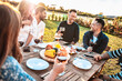 © Davide Angelini - Group of friends having fun at bbq outside dinner in home garden - Happy people cheering red wine sitting outdoor at dining table - Social gathering, youth, food and beverage concept