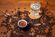 Czarna kawa espresso w czarnej filiżance i szklanka wody  na stole pełnym świeżo palonych ziaren kawy