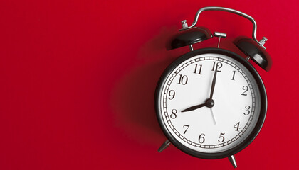 Wall Mural - vintage old black alarm clock on red background	