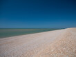 The open expanse of deserted shingle beach at Dungeness, Kent, UK. Taken on a sunny day in summer.