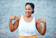 © N Lawrenson/peopleimages.com - Black woman, pointing and happy feeling proud and self assured choosing herself against city building wall, mockup space or outside in Nigeria. Portrait of African model with a fun or playful gesture