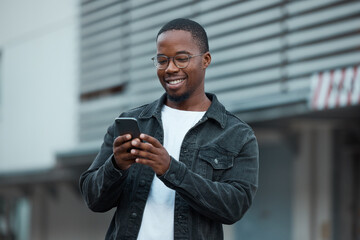 black man, phone and social media in city reading text message or communication on social network ap