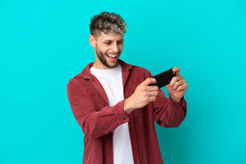 Poster - Young handsome caucasian man isolated on blue background playing with the mobile phone