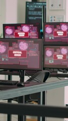 Vertical video: Empty agency office with multiple monitors showing system crash warning on display, critical error message flashing on screen. Computers displaying security breach malfunction at desk.