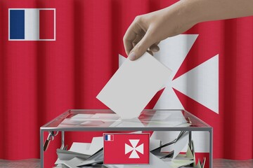 Wall Mural - Uvea flag, hand dropping ballot card into a box - voting/ election concept - 3D illustration