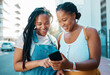 © Nina Lawrenson/peopleimages.com - African woman friends with smartphone in urban city reading social media post, check location on digital app or internet search for youth lifestyle. Teenager couple on 5g cellphone chat or networking