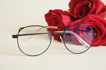 Poster - eye glasses and red roses on beige background