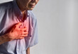 Asian man suffering from central chest pain. Chest pain can be caused by heart attack, myocardial infarct or ischemia, myocarditis, pneumonia, stress, anxiety, etc,.