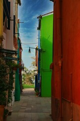 Poster - Vertical shot of narrow street with multicolored residential buildings under blue sky in Europe