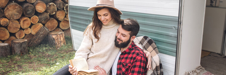 Young beautiful loving couple travelling across country in the van. Millennial man and woman in a travel camper. Cozy atmosphere, vacations vibe. Banner copy space