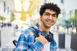 Egyptian student wearing headphones smiling to the camera while standing with backpack. Education concept 