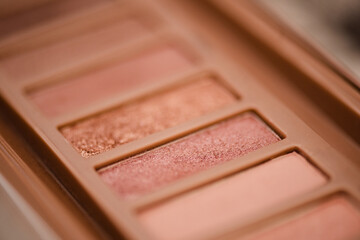 Wall Mural - Eye shadow palette in pink rose gold and nude colors closeup. Makeup cosmetic product. Selective focus.