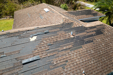 Poster - Damaged house roof with missing shingles after hurricane Ian in Florida. Consequences of natural disaster