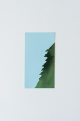 Sticker - green foil shape (half tree) on blue paper with texture