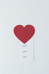 Sticker - red paper heart with textured pattern and the trilingual word one, uno, une