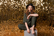 Happy beautiful girl in black hat in studio against background shiny golden wall, cute smiling caucasian young woman, holidays concept. New Year, Christmas or birthday