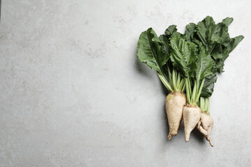 Fresh sugar beets with leaves on light grey table, flat lay. Space for text