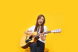 © snowing12 - Women are playing acoustic guitar and singing the song over isolated yellow background