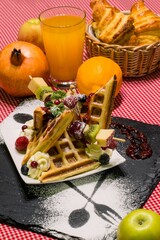 Sticker - Closeup of delicious dessert, waffles with fruit, croissants, orange juice, served on black board