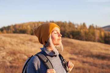 Middle aged woman hiking and going camping in autumn forest