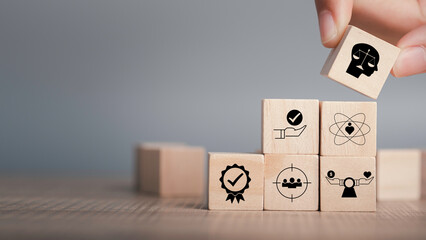 Wall Mural - Ethics inside human mind, Business ethics concept. Hand hold ethics inside a head symbols in wooden cubes stacked on gray background with copy space.