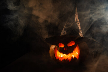 Wall Mural - A creepy pumpkin with a carved grimace in the smoke. Jack o lantern in the dark.